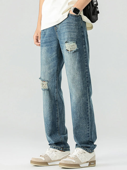Men's distressed relaxed jeans in vintage blue, side rips and worn back pocket