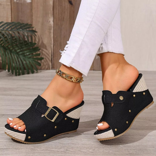 Black open-toe wedge sandal pair with ankle strap, square buckle, and stud details