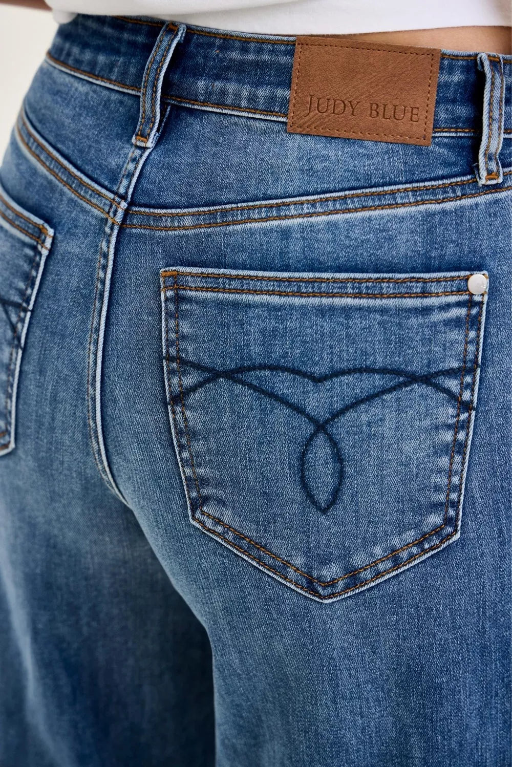 Judy Blue jeans close-up: leather-look logo patch and heart-stitched back pocket