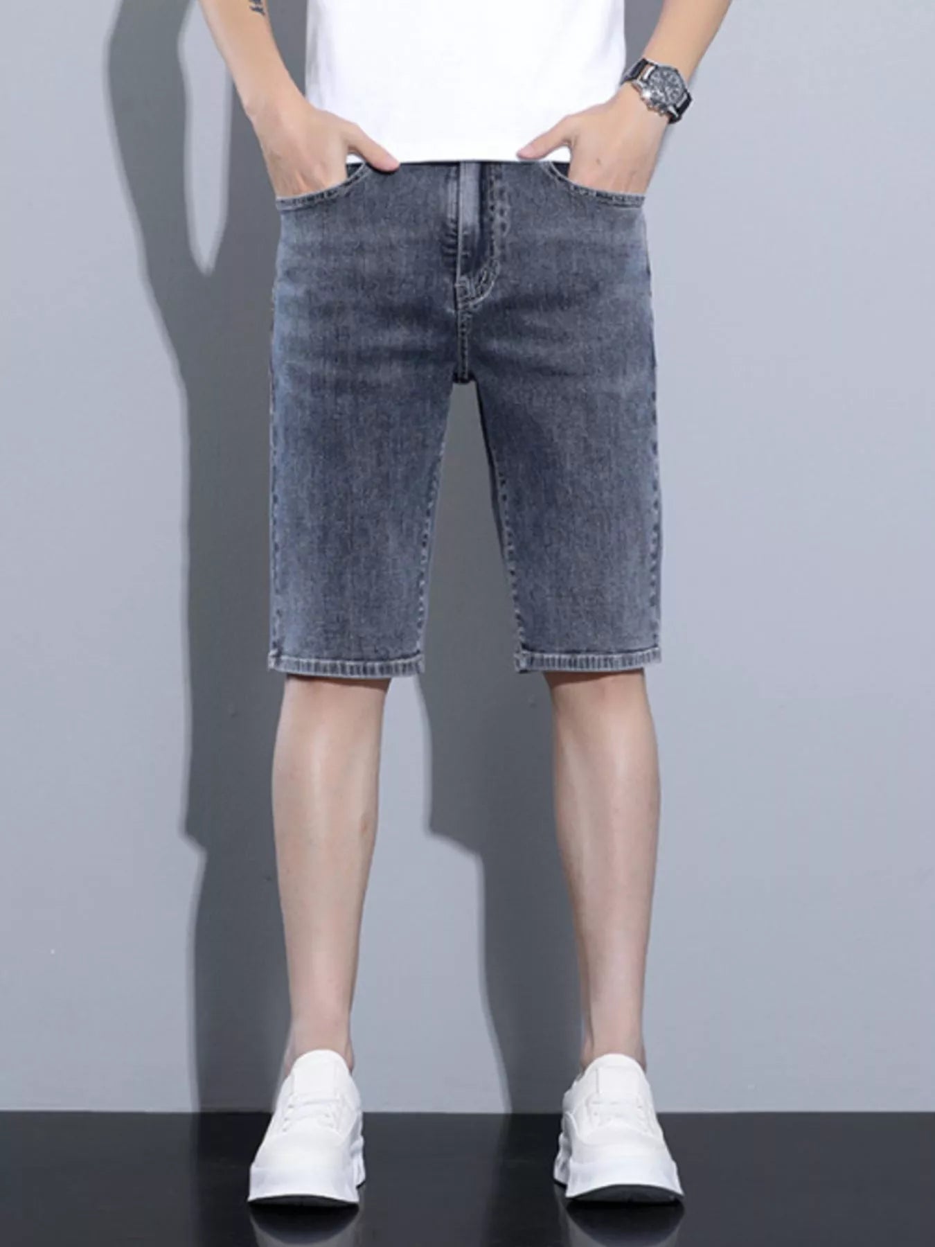 Dark blue gray denim wash shorts on model, cuffed hem, front button fly, pockets