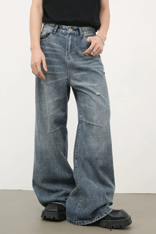 Medium-wash wide-leg jeans with distressed patches, side seam detail, button fly