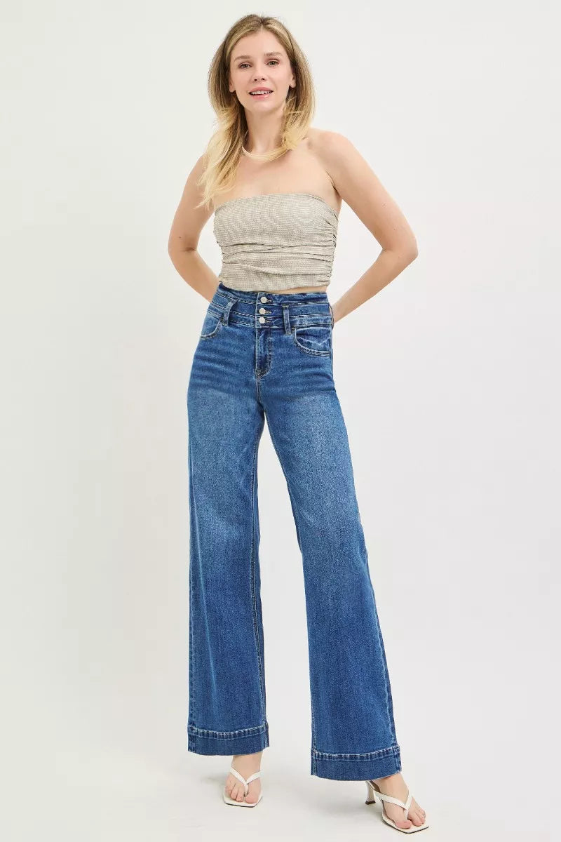High-rise wide-leg jeans on model, dark blue denim with button-fly and wide straight legs.