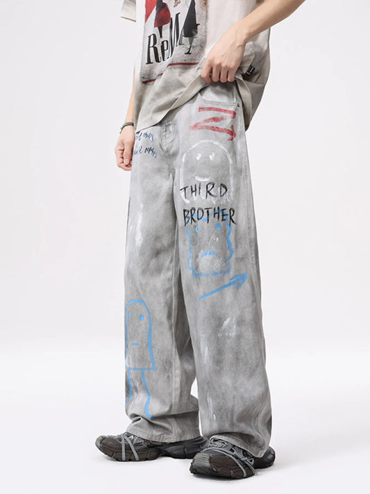 Light gray wide-leg jeans with faded graffiti artwork in blue and red across legs