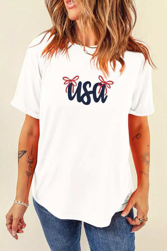 White T-shirt with embroidered USA lettering and bow details across the chest